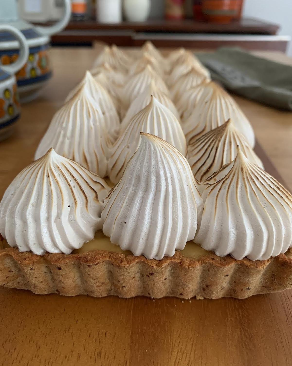 Gluten-free, dairy-free, refined sugar-free lemon meringue tart with a golden crust, creamy lemon filling, and lightly toasted meringue peaks