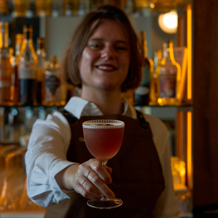 Bartender presenting a handcrafted cocktail at the bar at Chez Bagou, Albert Park