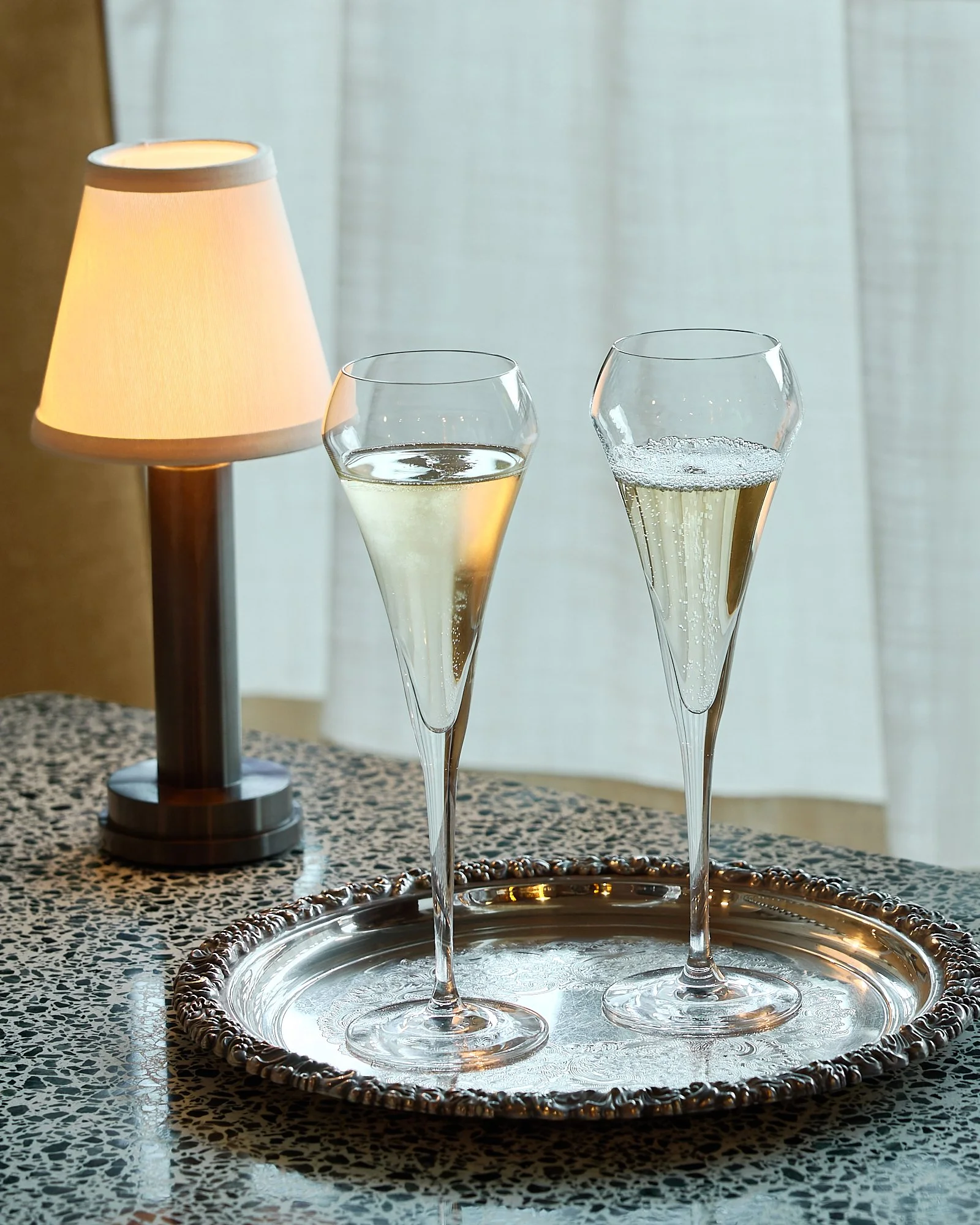 Two champagne flutes with a glowing table lamp at Chez Bagou