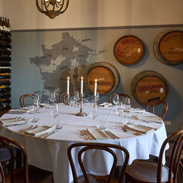 Cellar dining room with round table and wine barrel décor at Chez Bagou, Albert Park