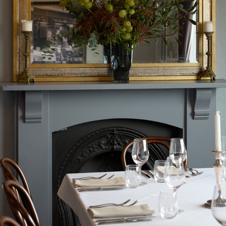 Dining table beside the fireplace with floral arrangements at Chez Bagou, Albert Park Melbourne