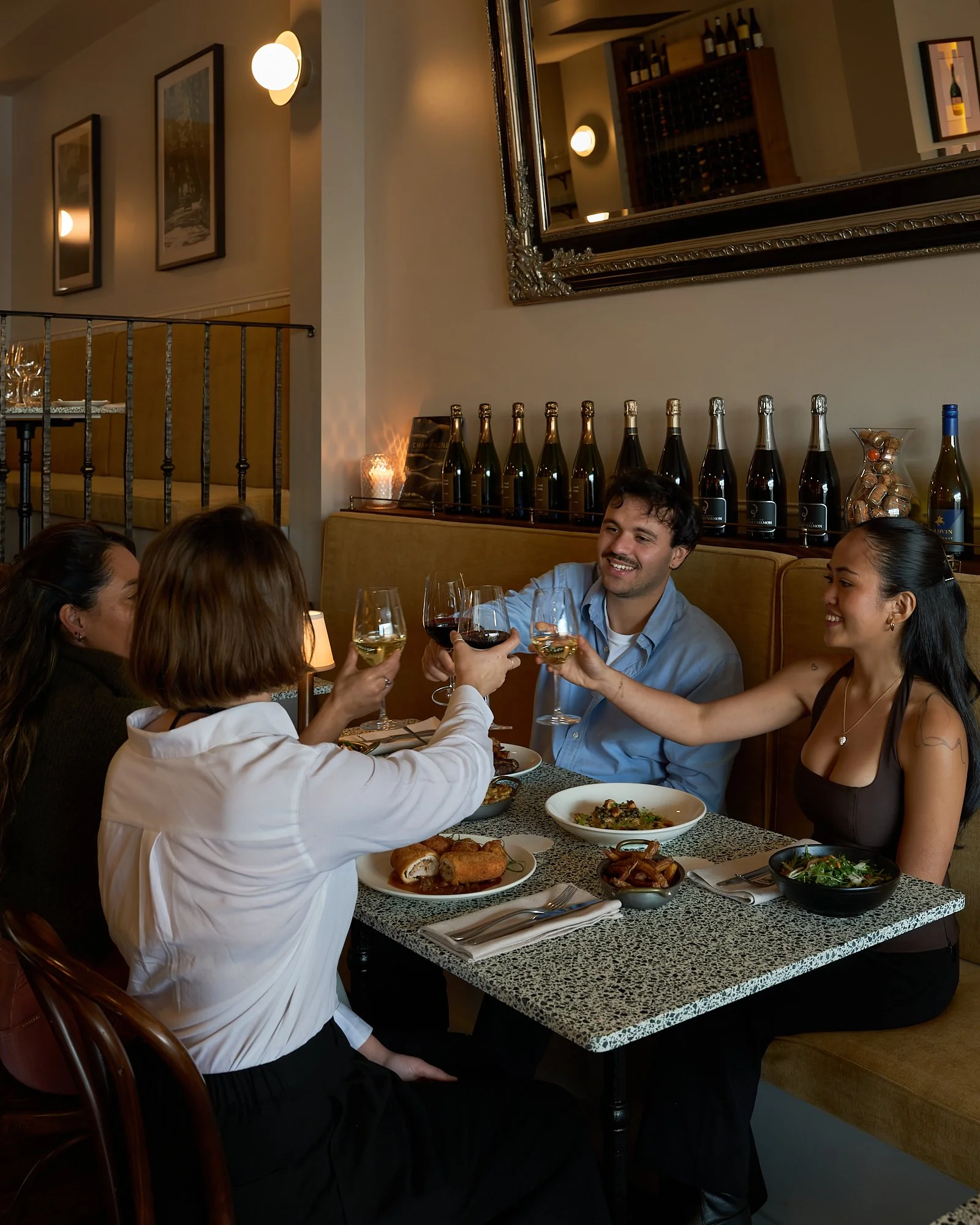 Friends toasting with wine at dinner at Chez Bagou French restaurant, Albert Park Melbourne