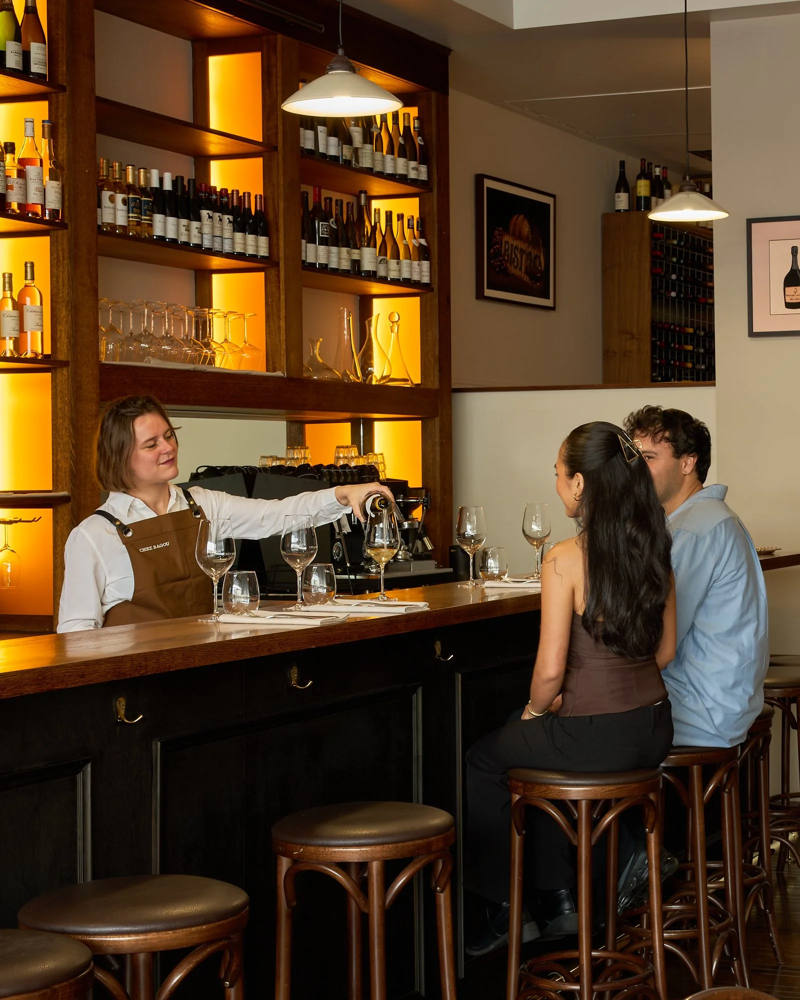 Bartender serving wine to guests at the bar at Chez Bagou, Albert Park Melbourne