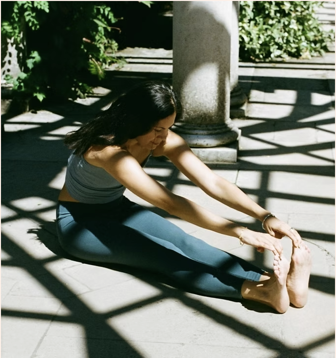 Female in seated forward fold yoga pose in the sunshine