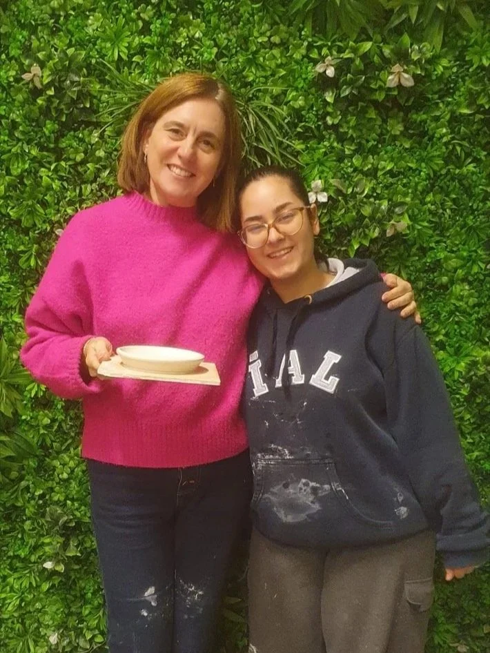 Clay Studio Leiden pottery student wheel-throwing a small conical shape in porcelain as her teacher carefully watches her