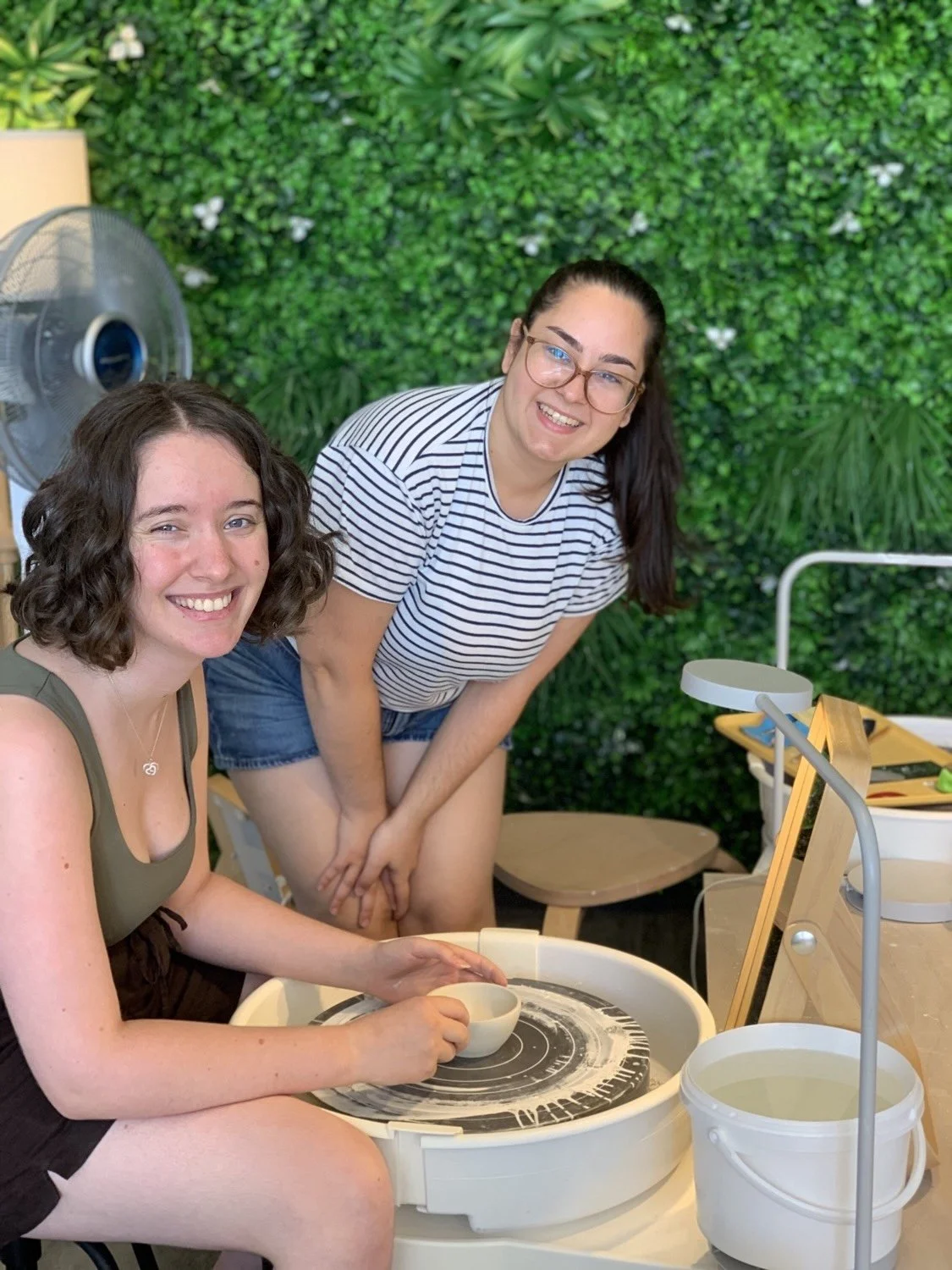 Clay Studio Leiden pottery student and teacher smiling at the camera as the student looks proud of the porcelain bowl she just finished working on