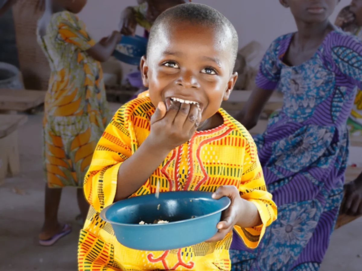 Little boy eating rice with a big smile on his face.