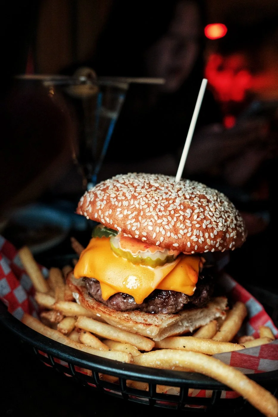 Cheeseburger with sesame seed bun, lettuce, pickles, american cheese, seasoned beef patty, served with fries.