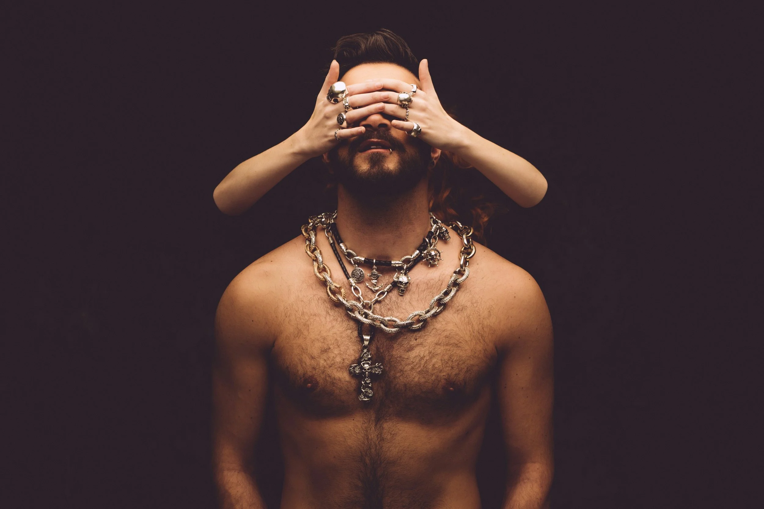 shirtless man with a woman's hands over his face