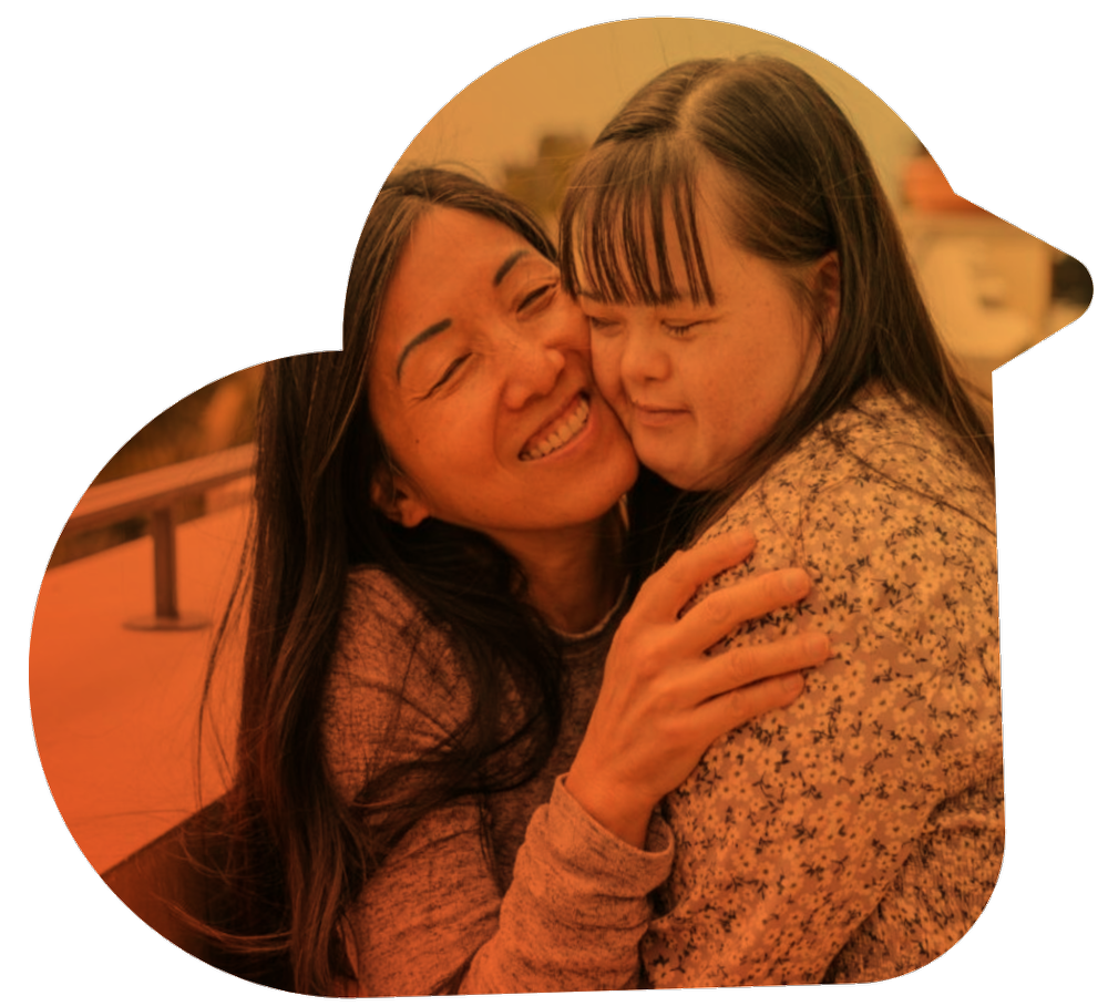 A smiling caregiver hugging a young woman