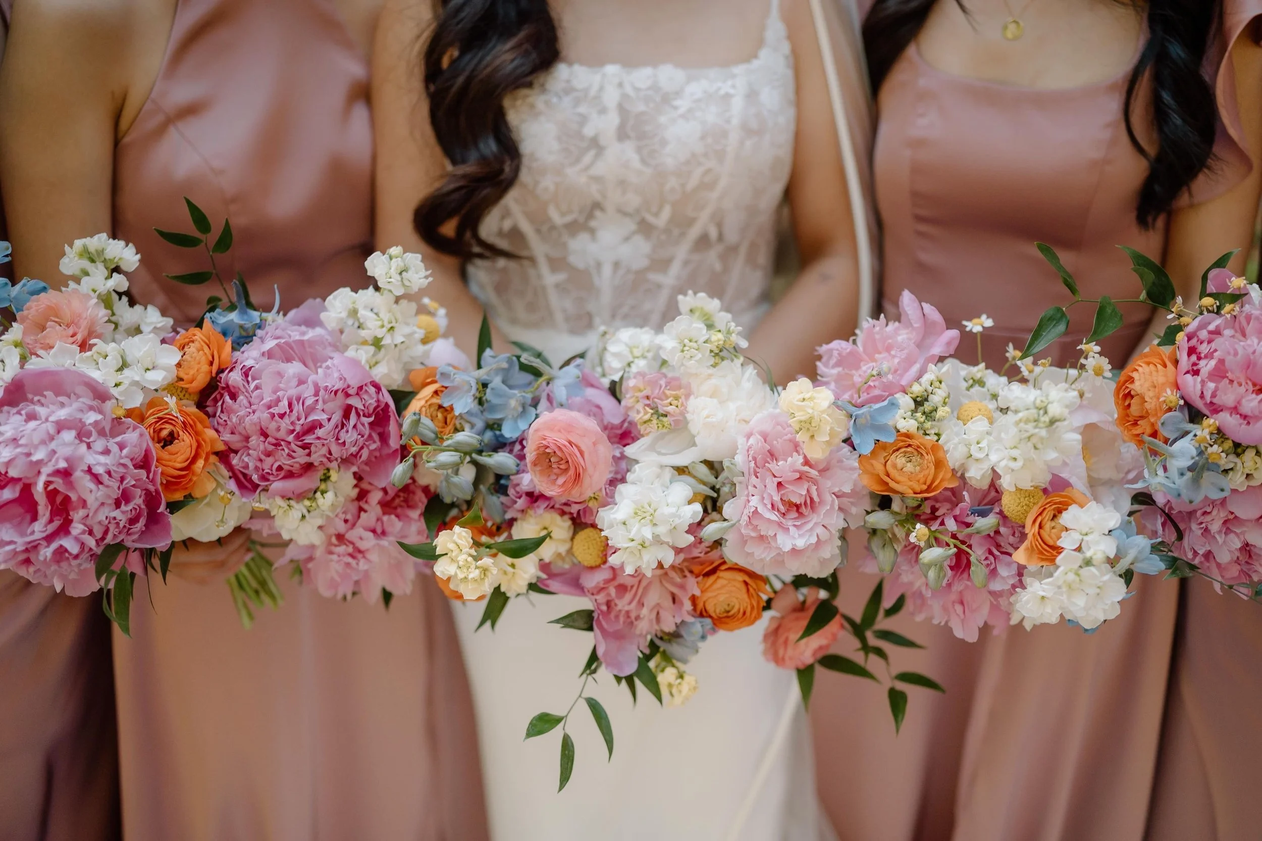 Colorful bouquet with dahlias, daisies, and various flowers held outdoors, surrounded by trees.
