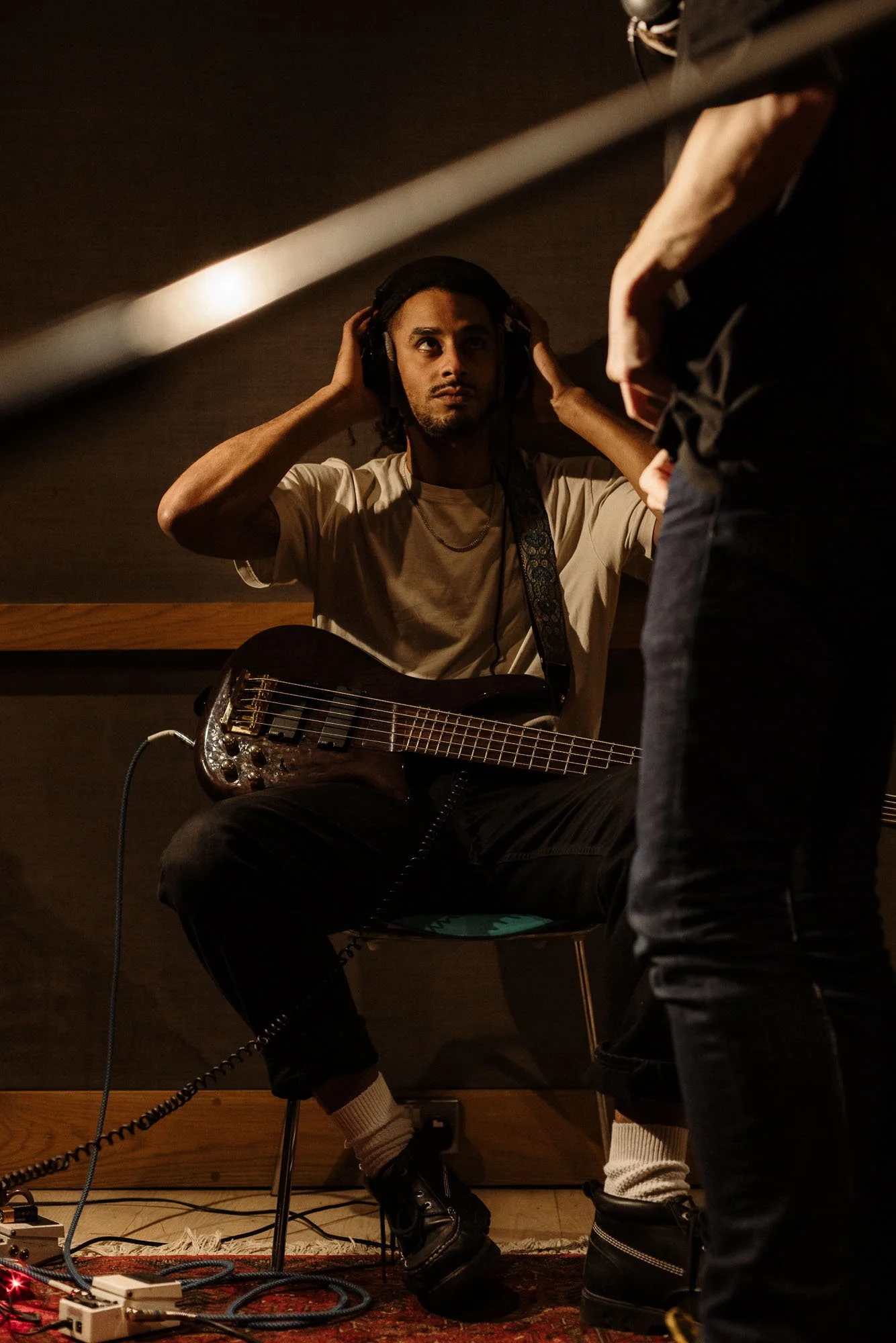 Guitar player sits on a chair and places headphones over his head