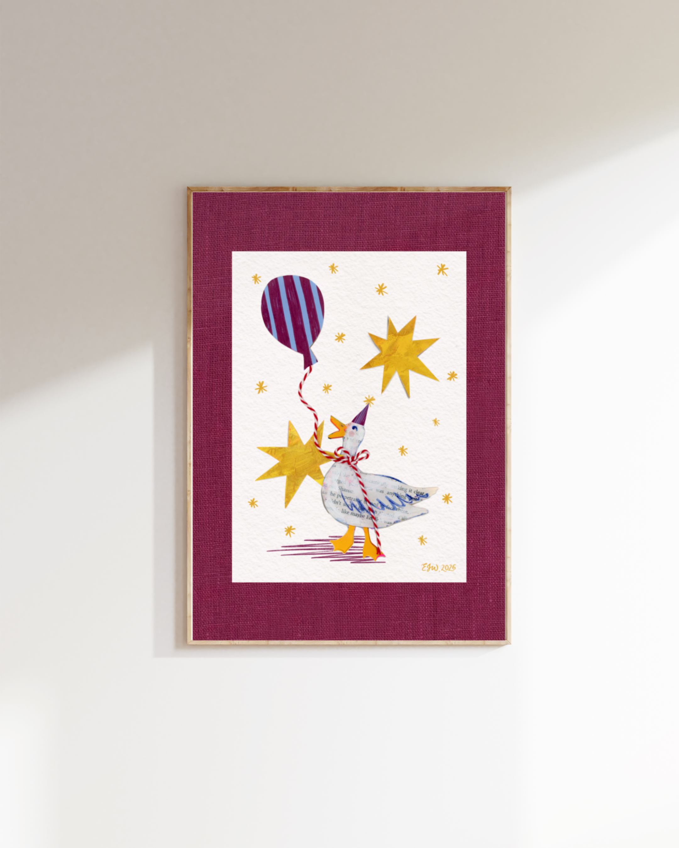 A framed artwork by Emma Winterschladen, hanging on a wall featuring a colorful illustration of a bird, a balloon, and stars, with a maroon border.