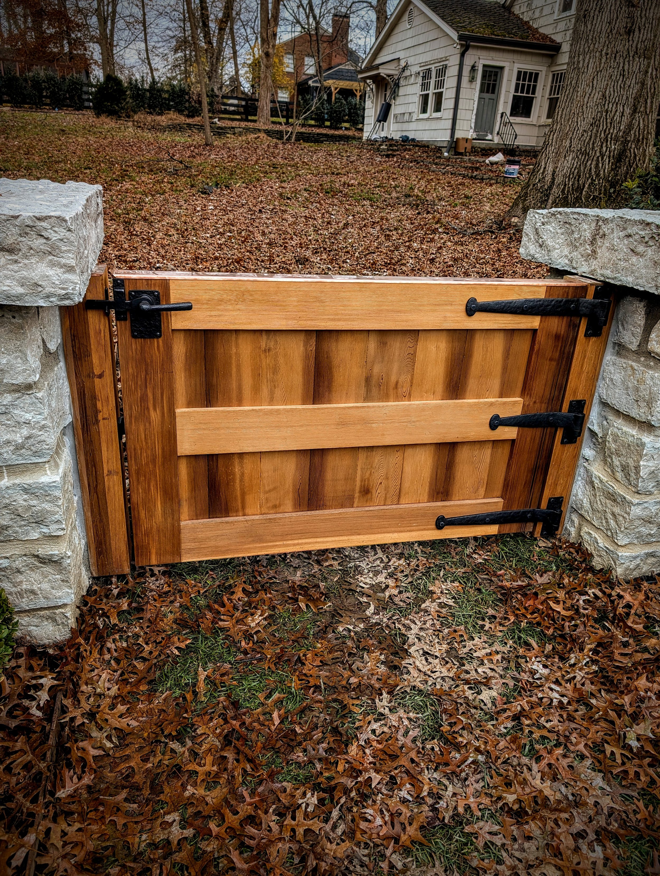 Cedar garden gates with hand hammered bronze hardware made in Italy.  Copper topping and jams anchored 8" into the stone pillars. 