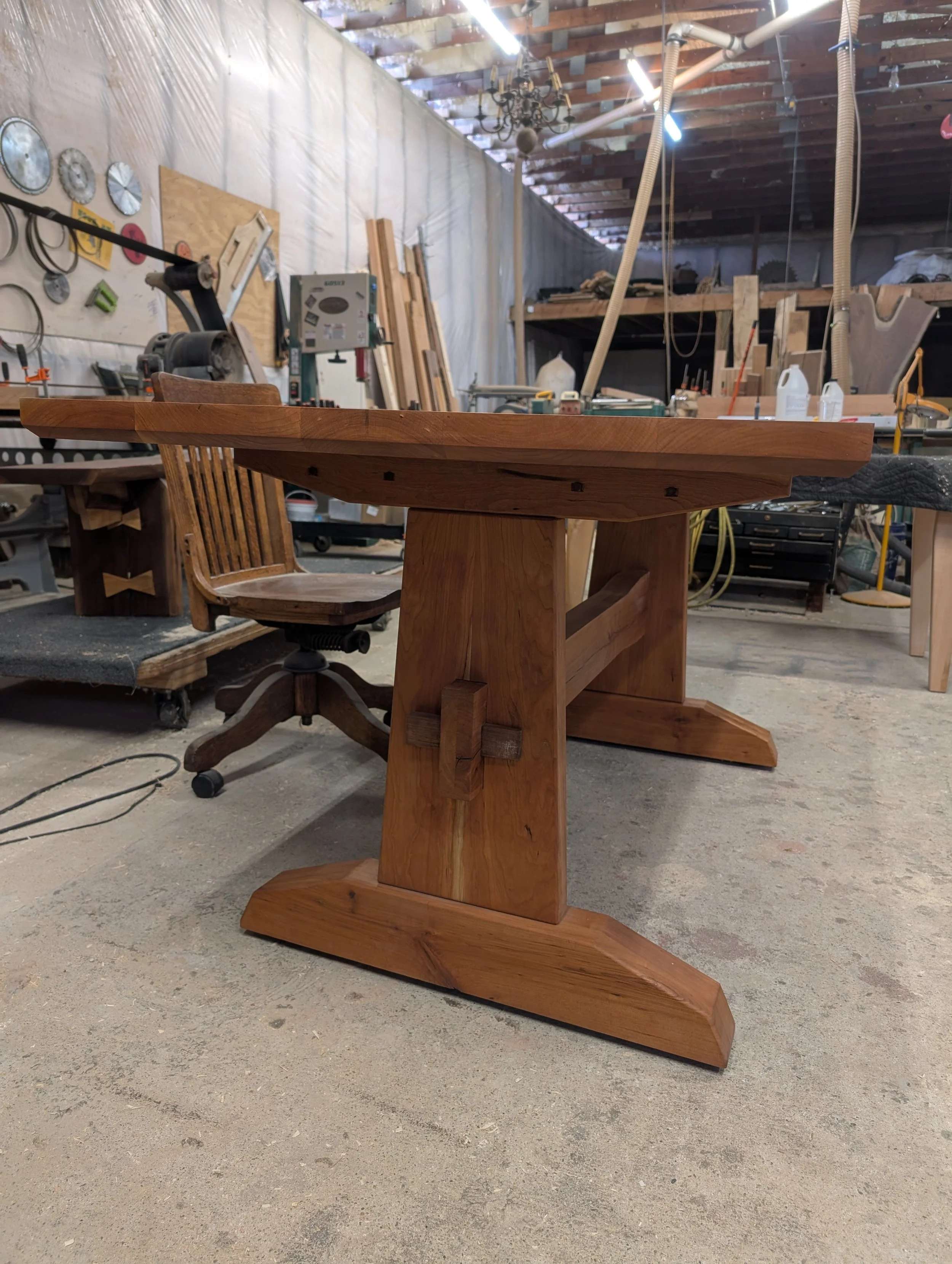 Our Harper table.  Trestle style base, entirely made of cherry.  A thick 1 5/8" thick top with removable hardware and wedges for moving.  Available in different species and sizes. 