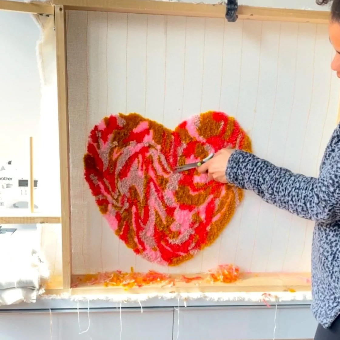 Person trimming a large heart-shaped floral arrangement on a wall.