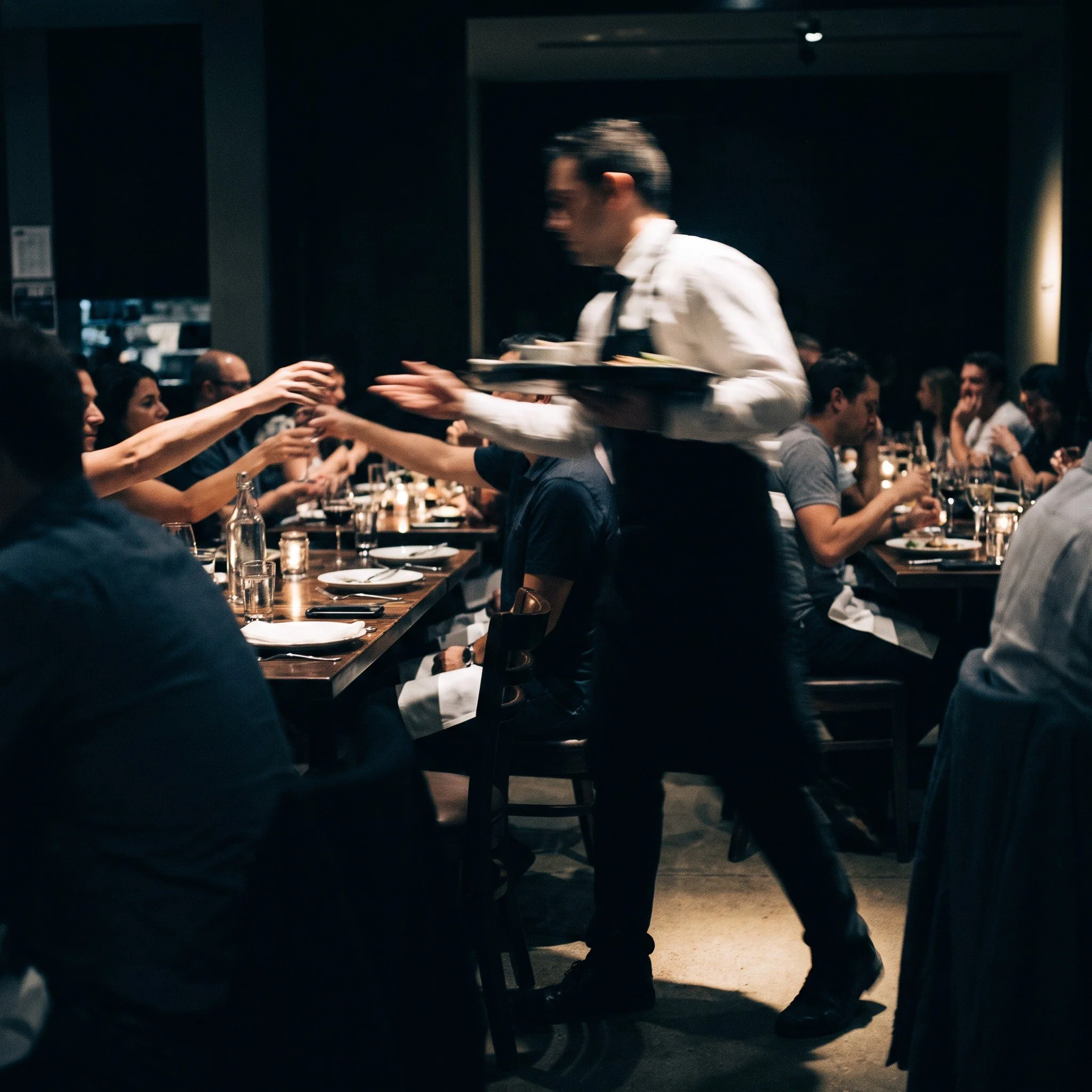 Busy restaurant at peak service with one waiter rushing between tables