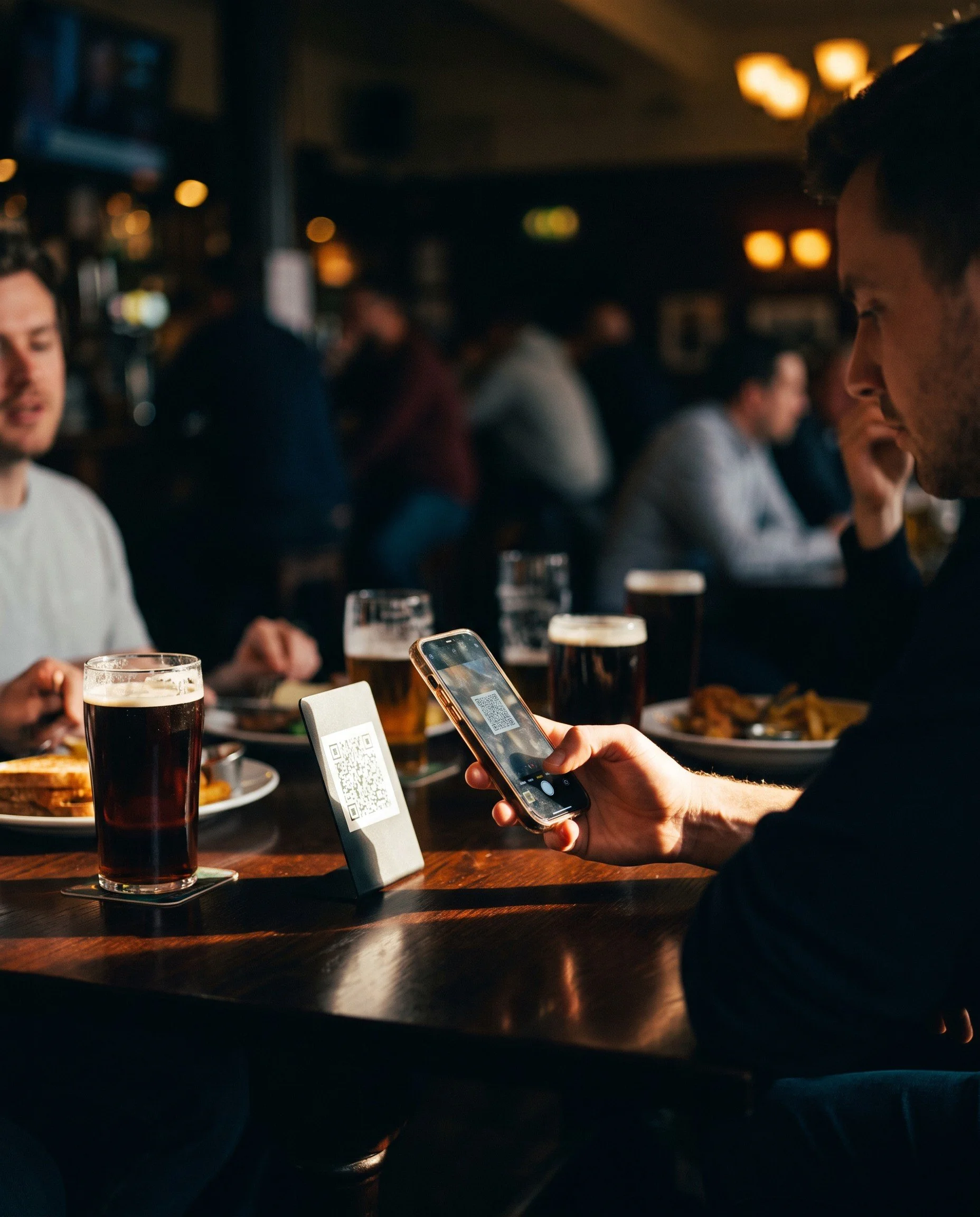 Pub guests scanning a QR code on the table to order food and drinks