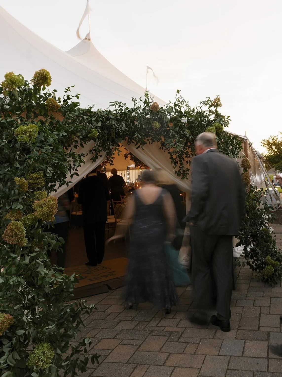 The change was never accidental. As daylight faded, the design revealed its second self. A tent meant to glow from within.

Candlelight gathered beneath the trees, chandeliers shimmered like stars, and the florals took on a new depth. What began as a