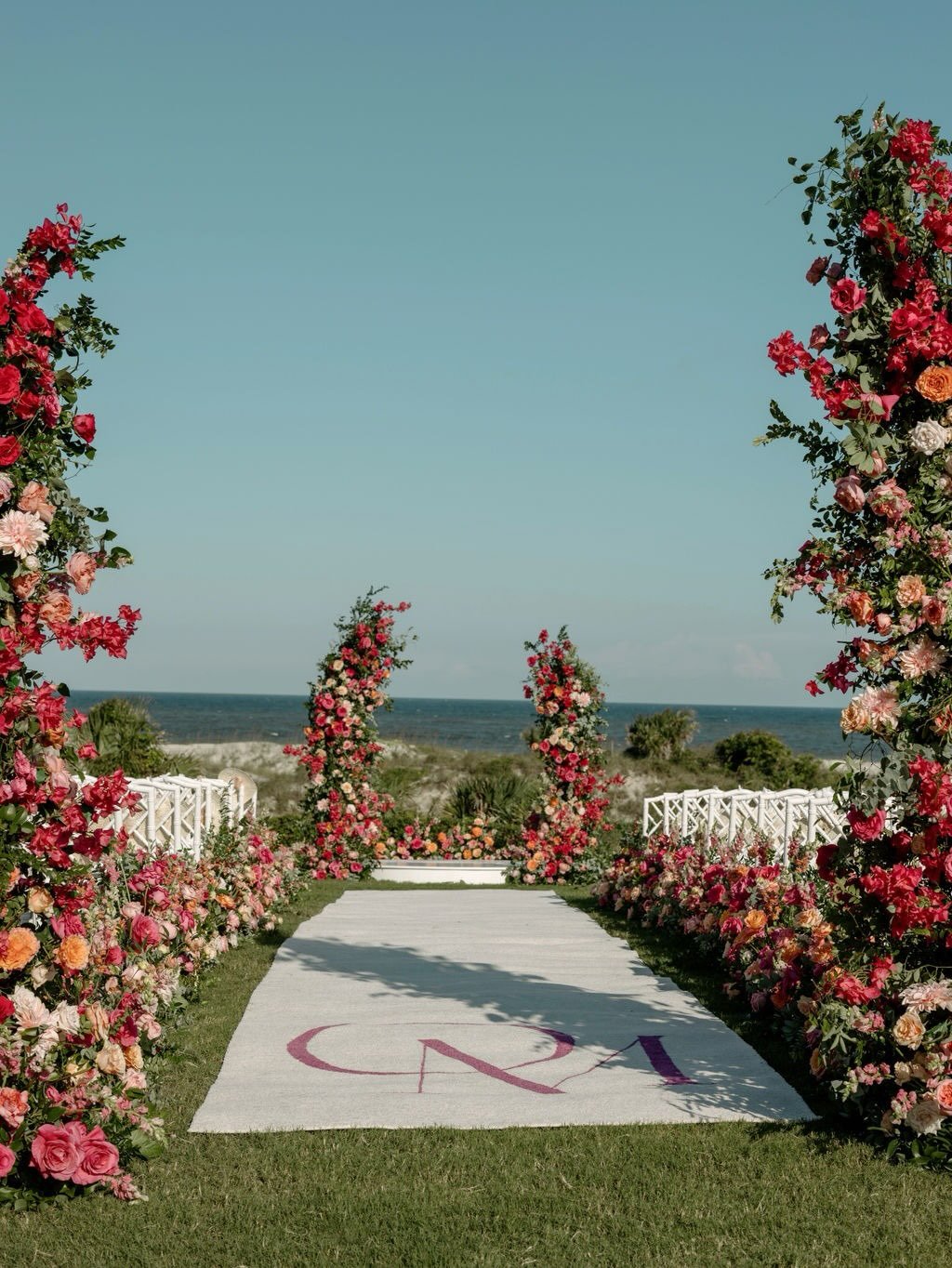 We&rsquo;re precise about continuity.

The floral runner carries the aisle in pinks, corals, and peach that stay consistent end to end, with the OM monogram set into the carpet so it lives within the design. 

At the altar, we scale that same palette