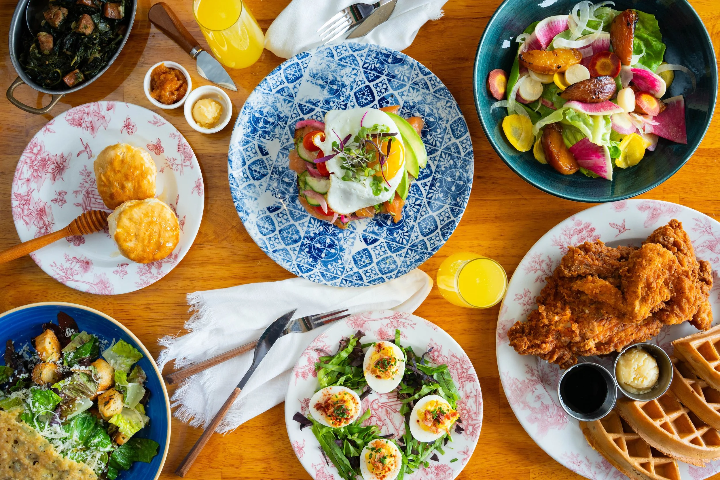 Ms. Peach's spread of food with salads, biscuits, appetizers, chicken & waffles, with mimosas spread throughout