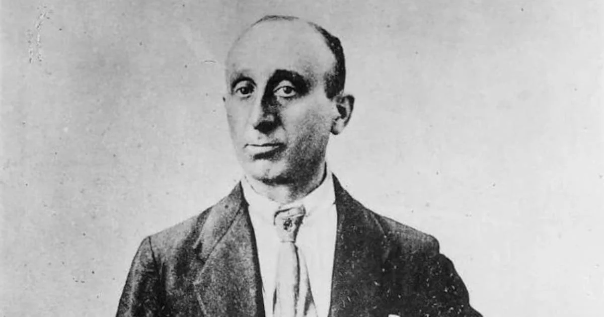 Black and white photo of a man wearing a suit and tie, with a serious expression.