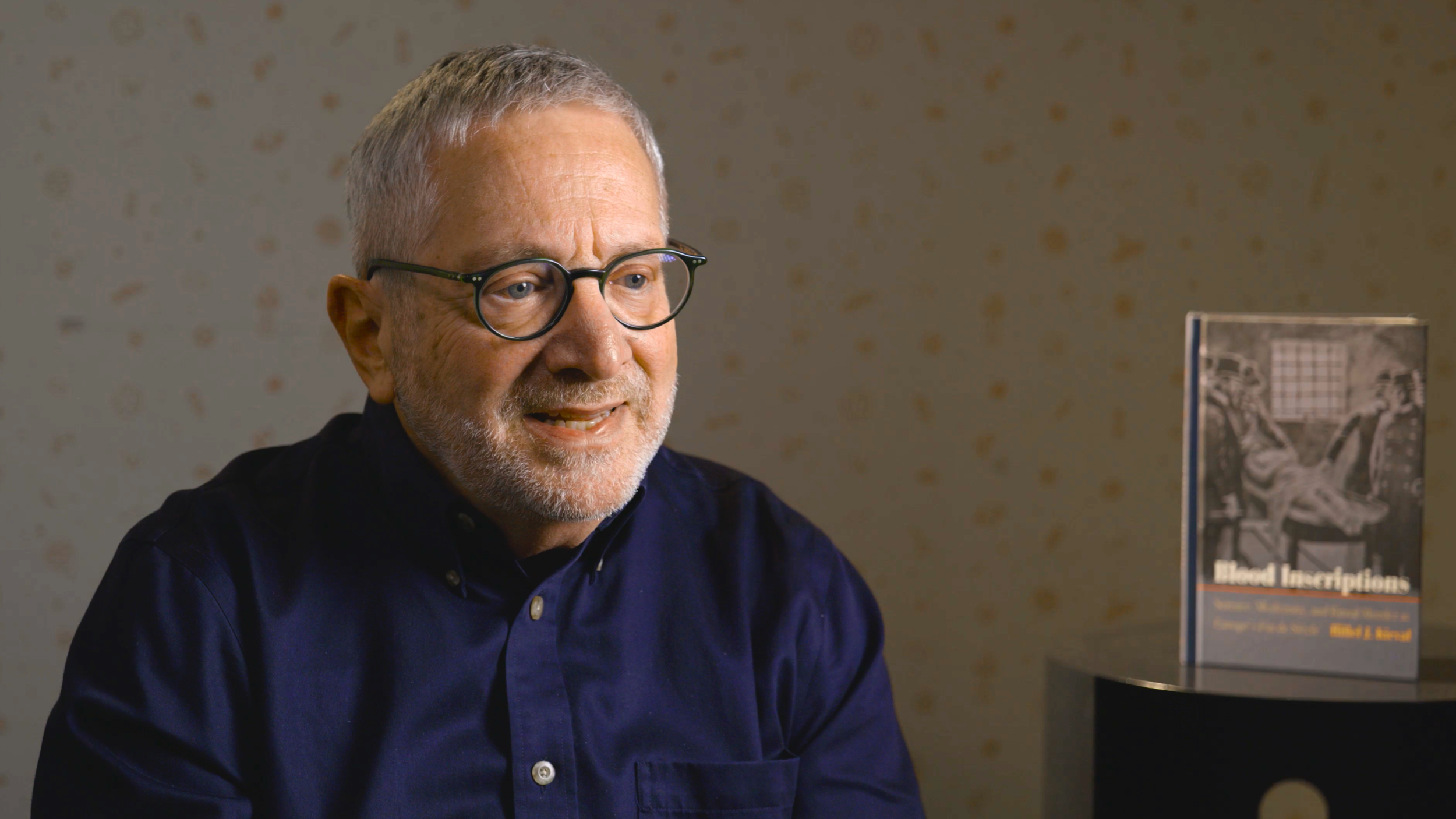 Hillel Kieval being interviewed for The Future Shapes the Past sitting next to his book 'Blood Inscriptions' on a table.