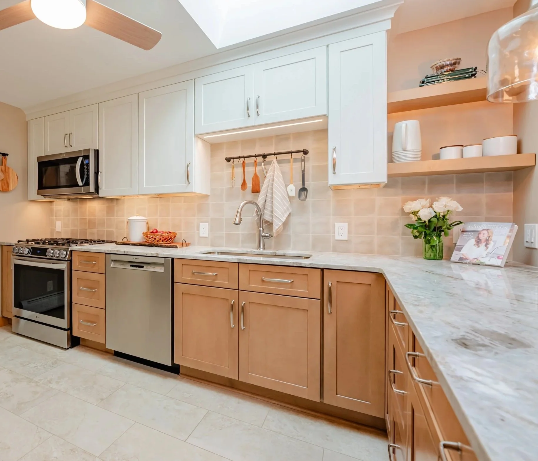 Kitchen remodel in Rochester, NY with white upper cabinets, warm wood base cabinets, stainless appliances, light stone countertops, and tile backsplash