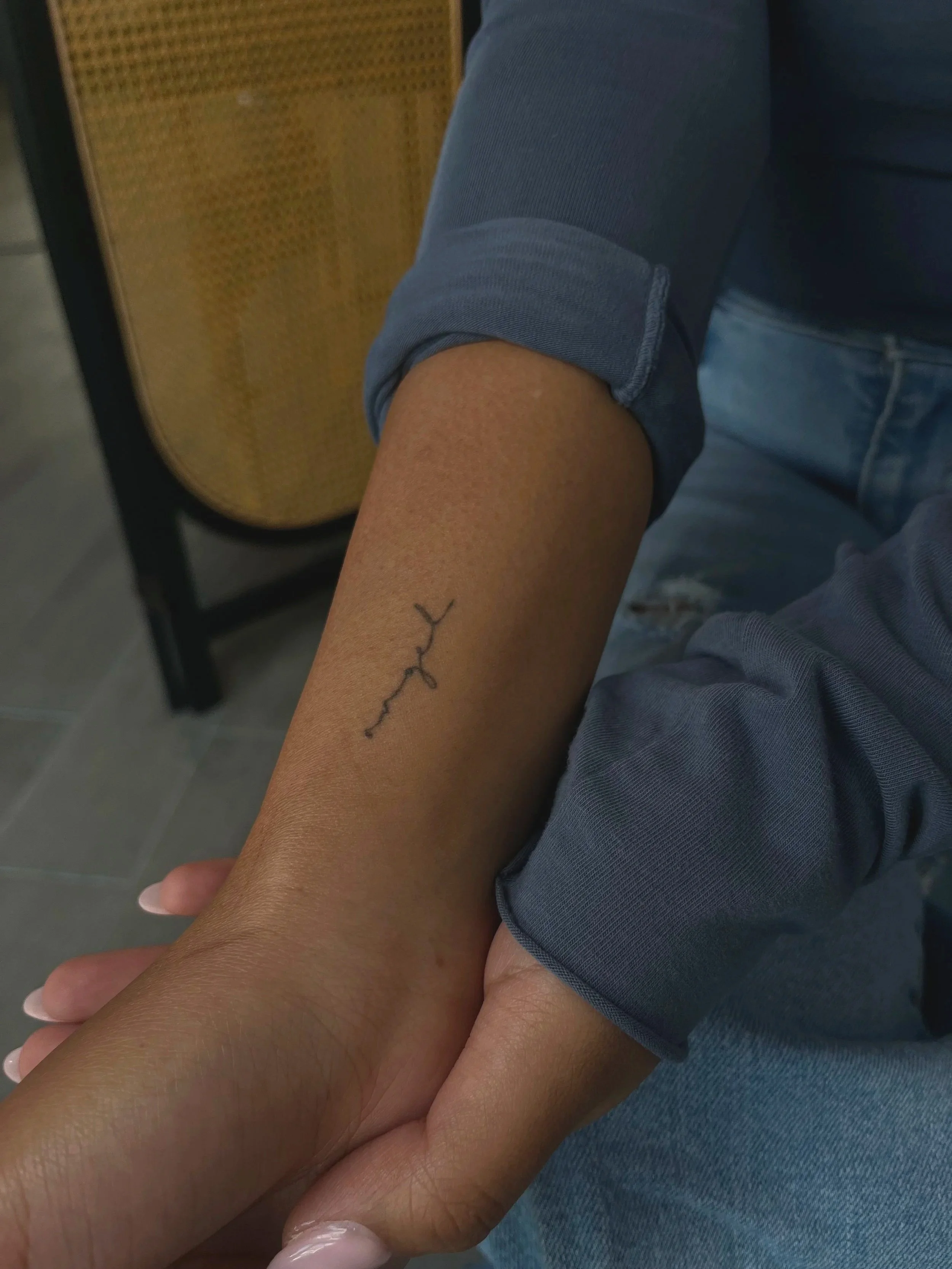 Arm with small minimal tattoo of a line with dots. single needle fine line inkpress mags studio ornamental font script smoke floral