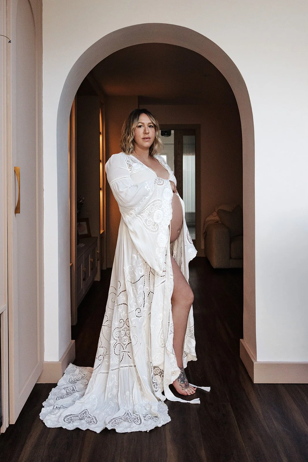 Pregnant woman in final week of pregnancy being gently posed and directed during at home maternity photoshoot with partner