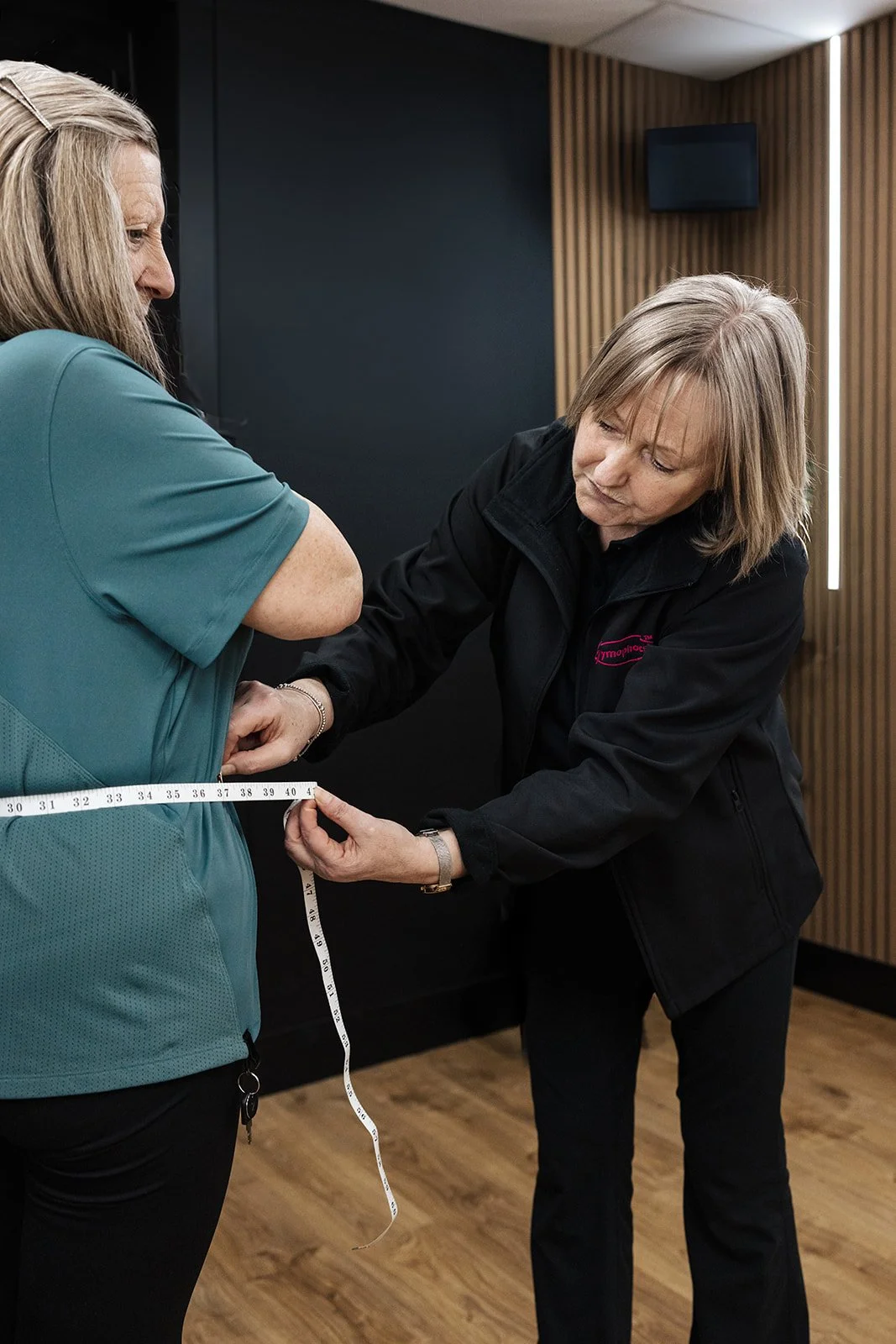 A female gym-goer smiling as she uses equipment in a bright, welcoming fitness space.