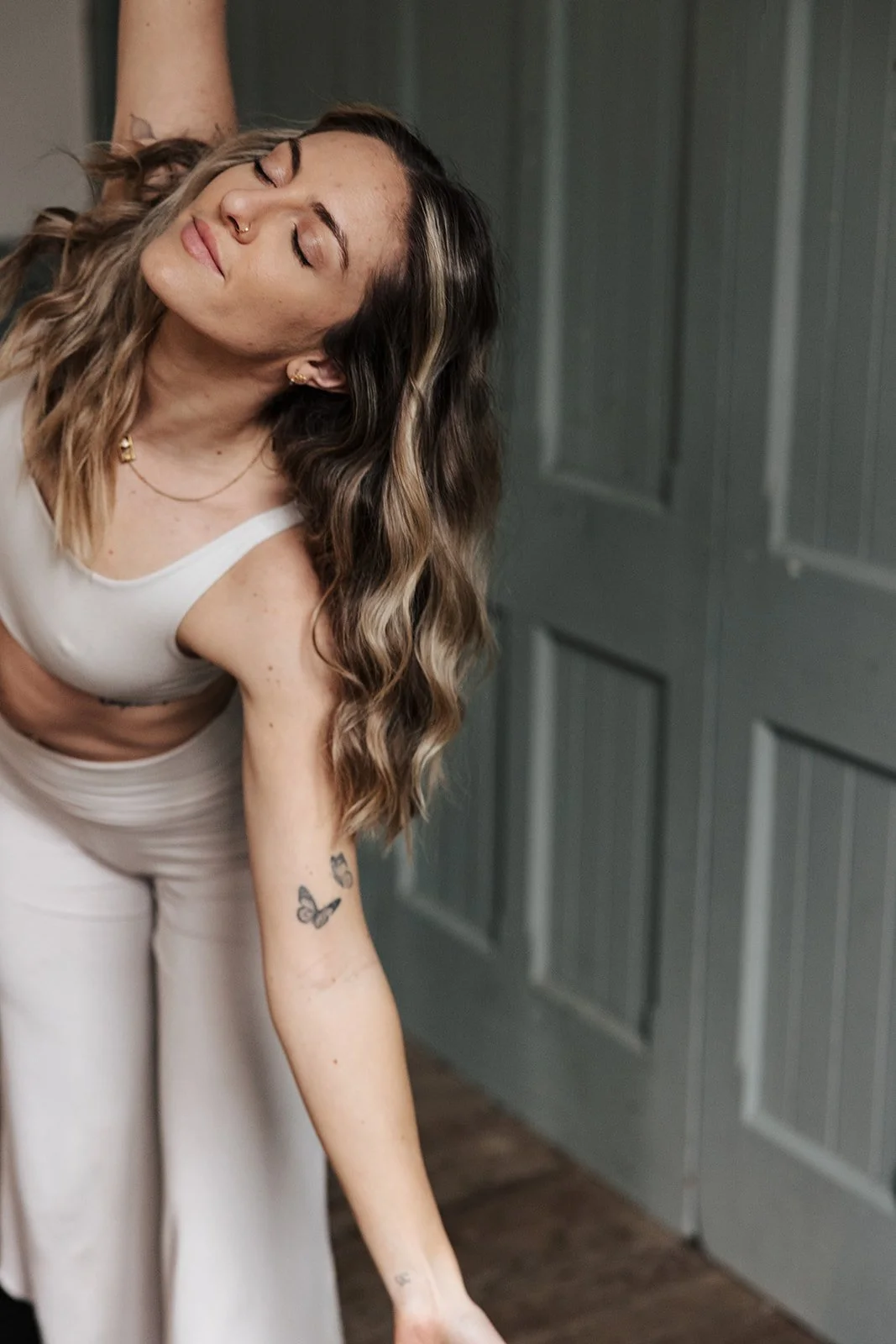 A woman with blonde hair wearing a yoga outfit going a yoga pose for her wellness business.