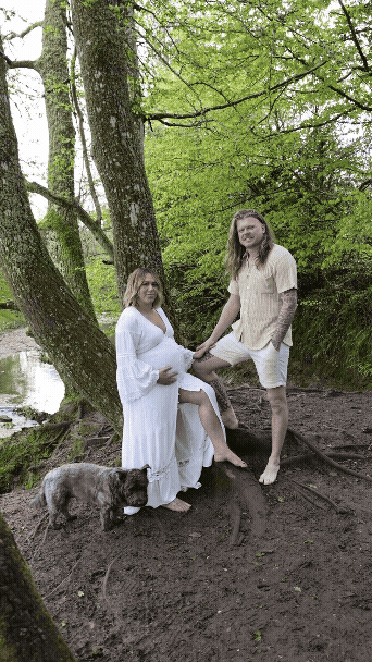 Pregnant woman in final week of pregnancy being gently posed and directed during at home maternity photoshoot with partner
