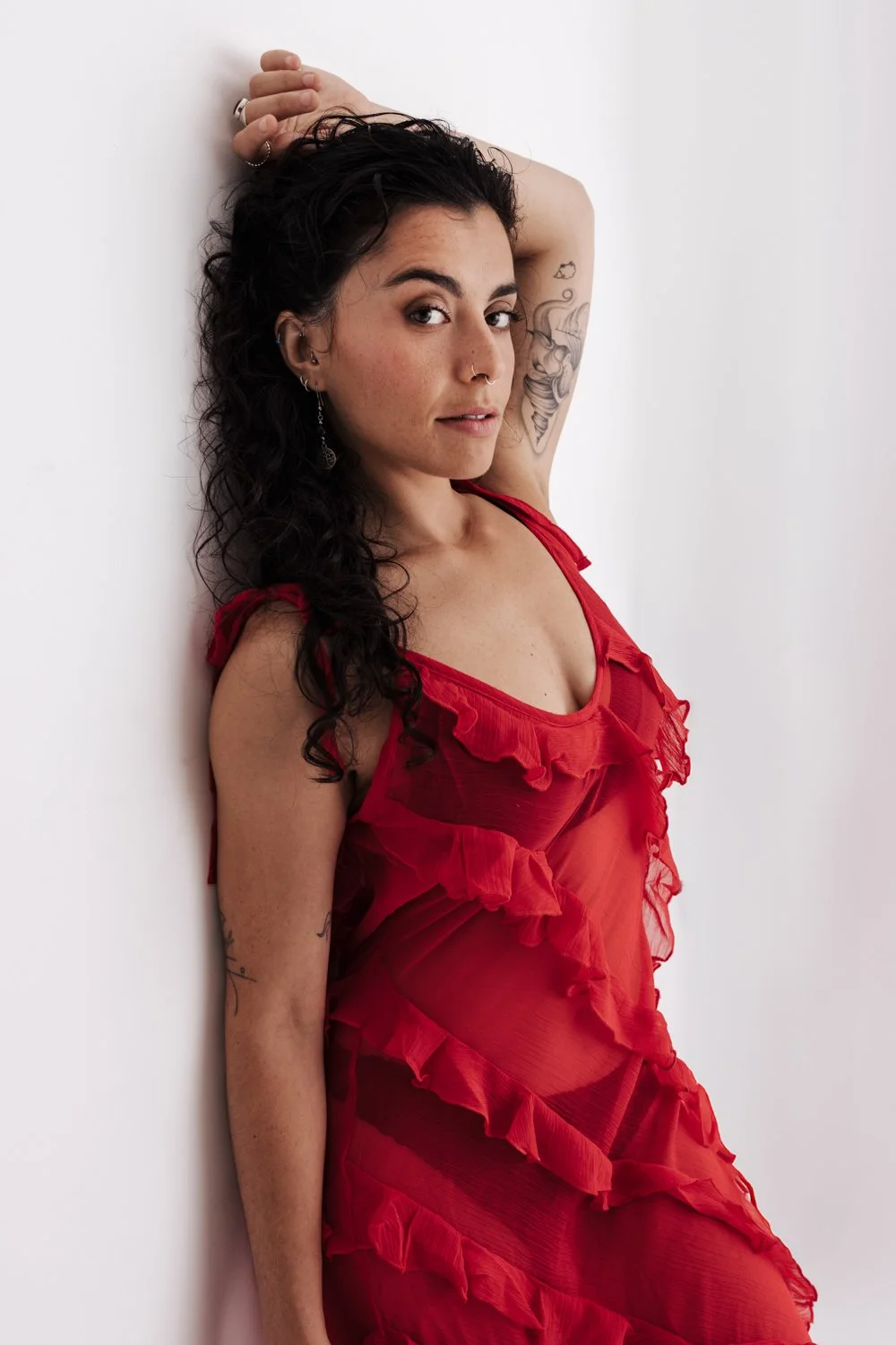 Woman posing in a red dress for a self-love portrait session in a studio
