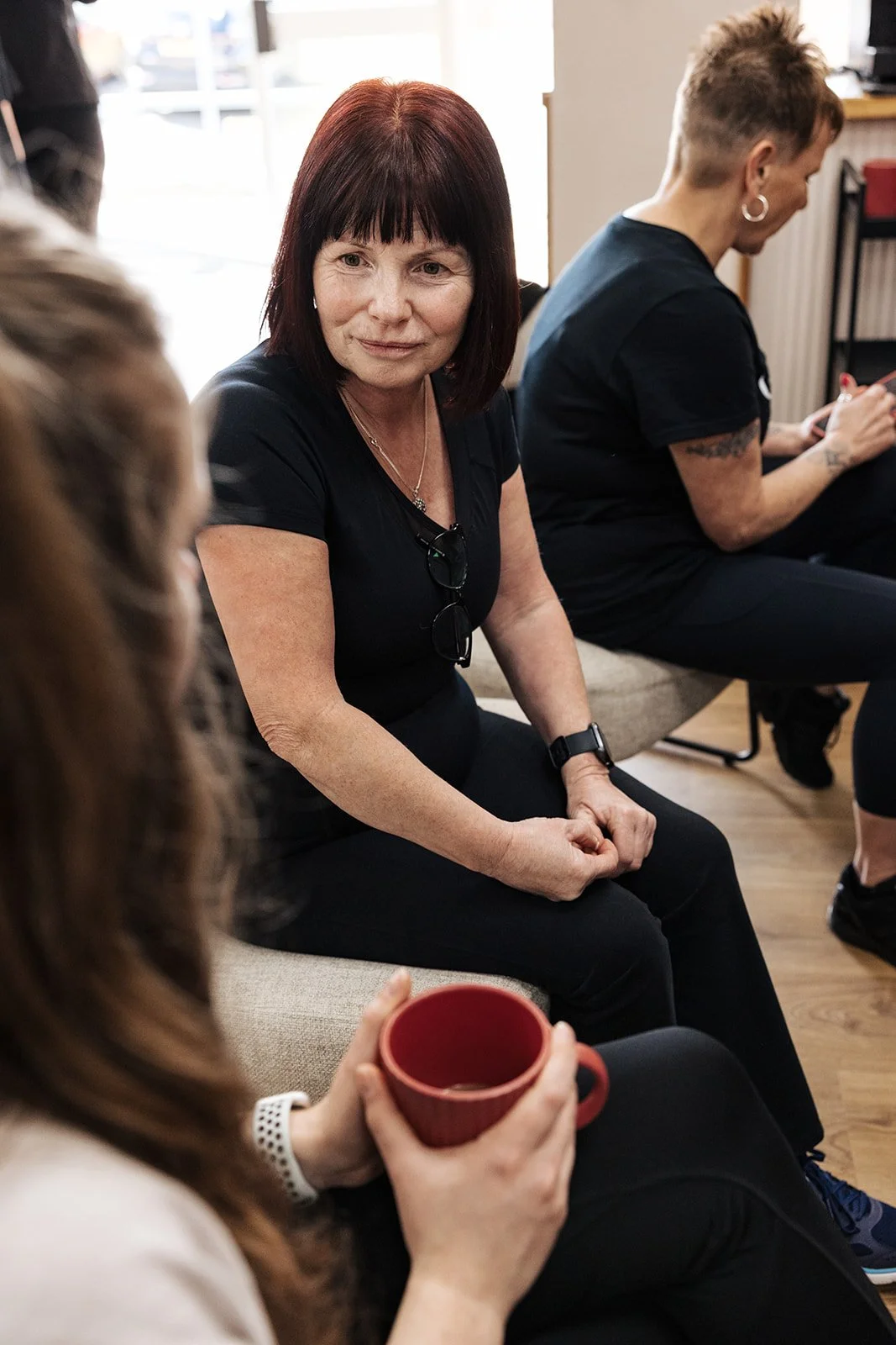 A female gym-goer smiling as she uses equipment in a bright, welcoming fitness space.