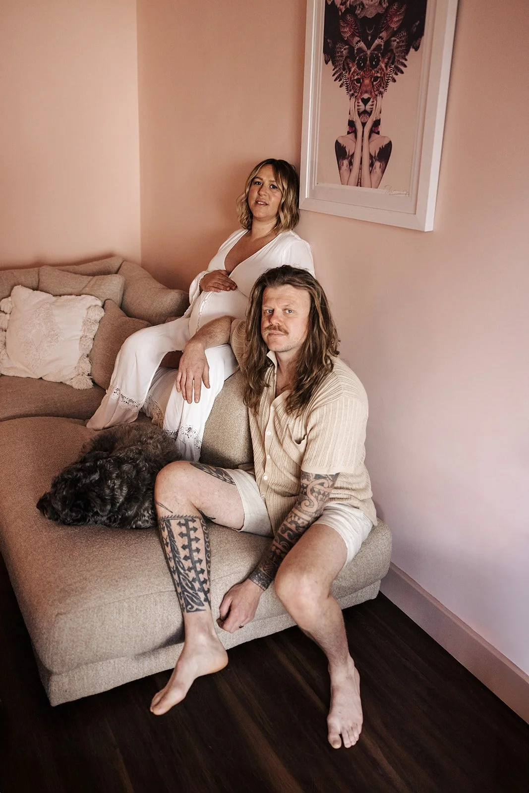 Pregnant woman in final week of pregnancy being gently posed and directed during at home maternity photoshoot with partner