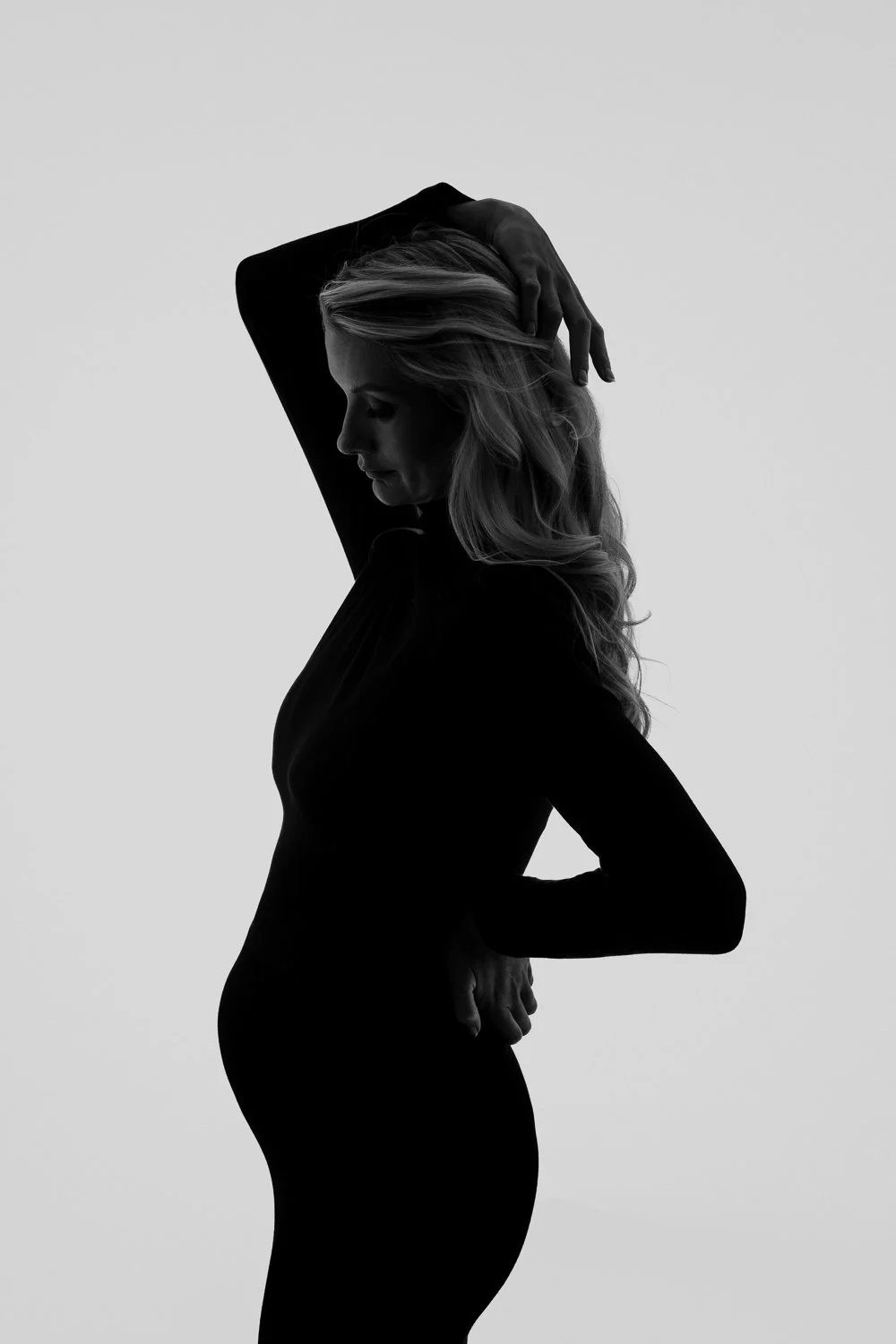 Simple and natural maternity photoshoot pose highlighting pregnancy in a relaxed studio photography session.