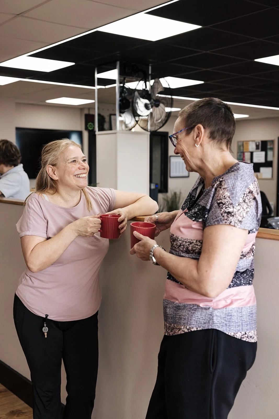 A female gym-goer smiling as she uses equipment in a bright, welcoming fitness space.