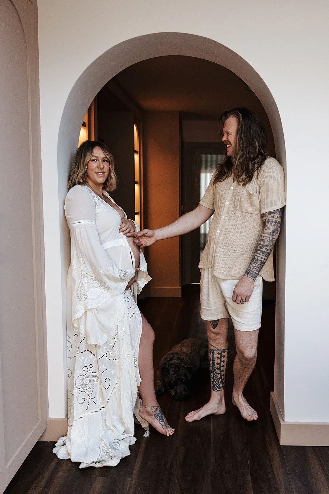 Pregnant woman in final week of pregnancy being gently posed and directed during at home maternity photoshoot with partner