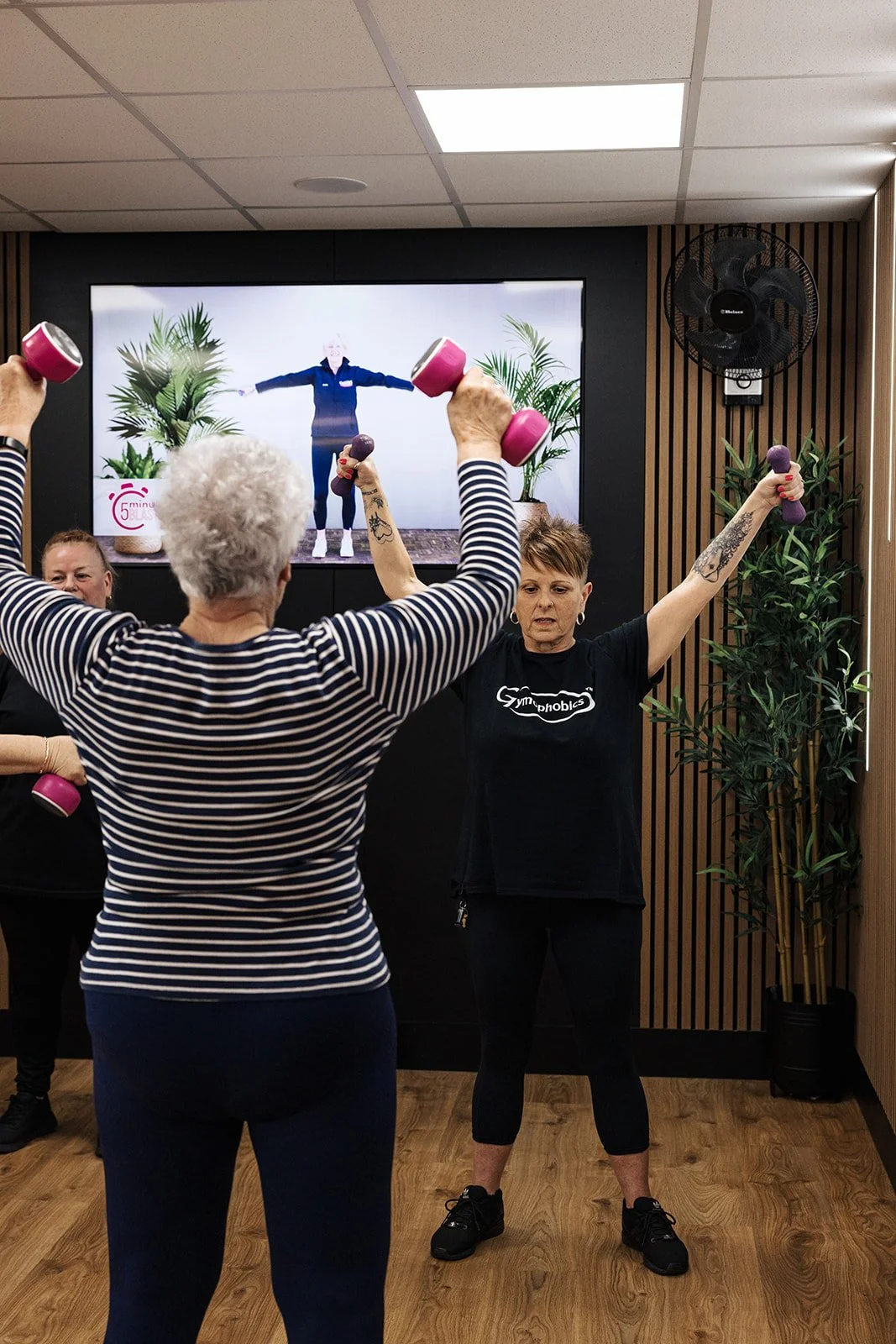 A female gym-goer smiling as she uses equipment in a bright, welcoming fitness space.