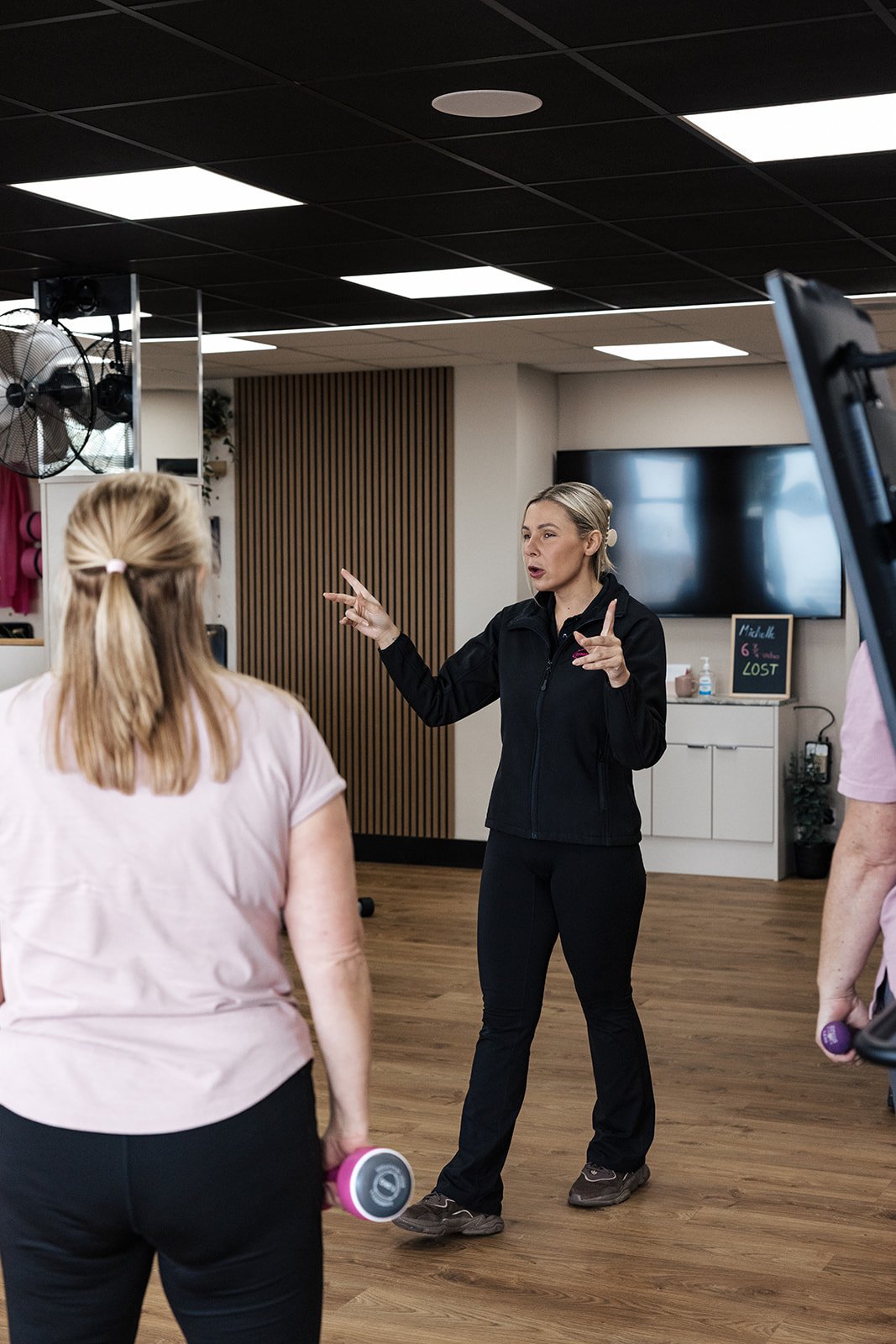 A female gym-goer smiling as she uses equipment in a bright, welcoming fitness space.