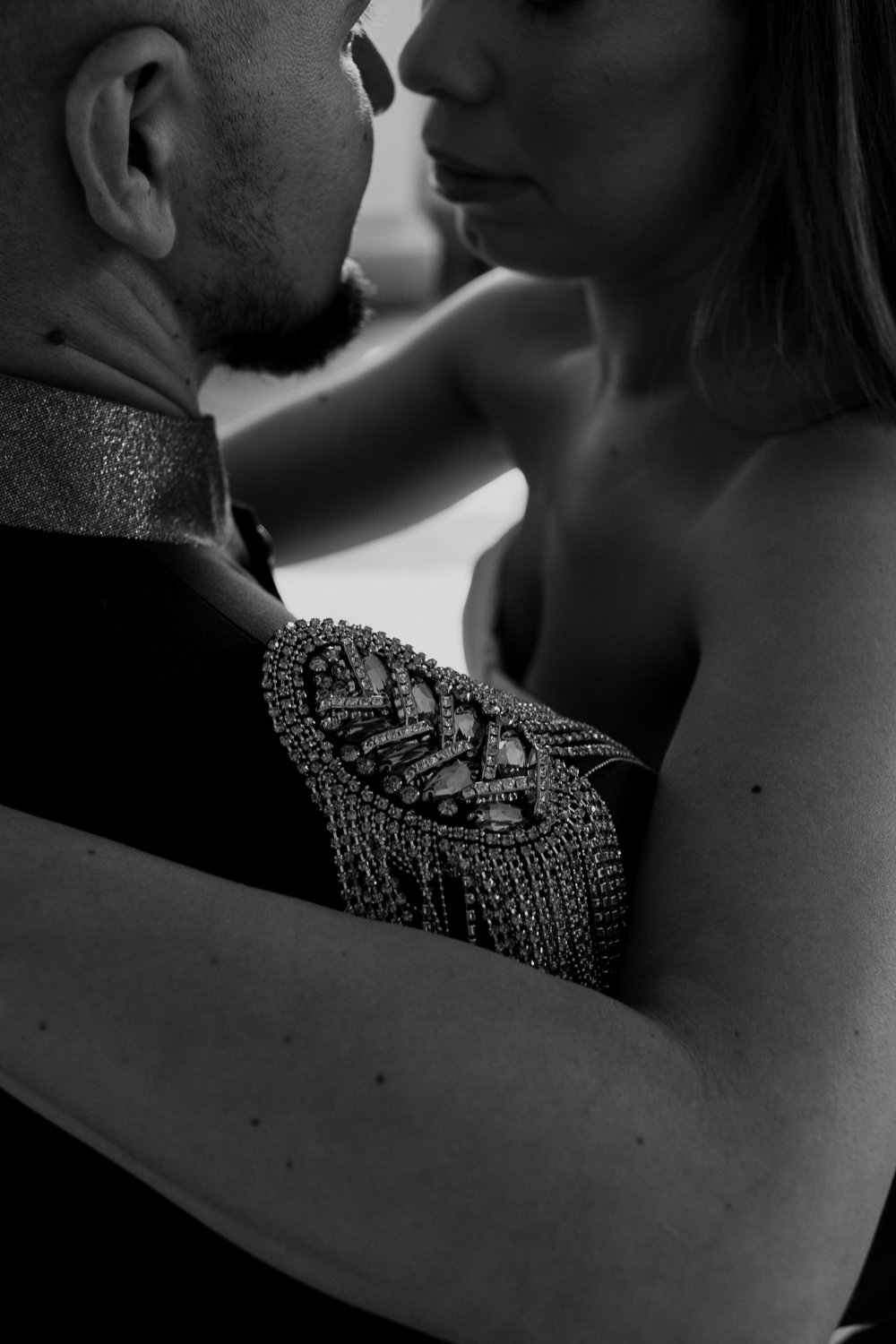Close-up of a man and woman in an intimate embrace, with their faces close together, black and white photograph.