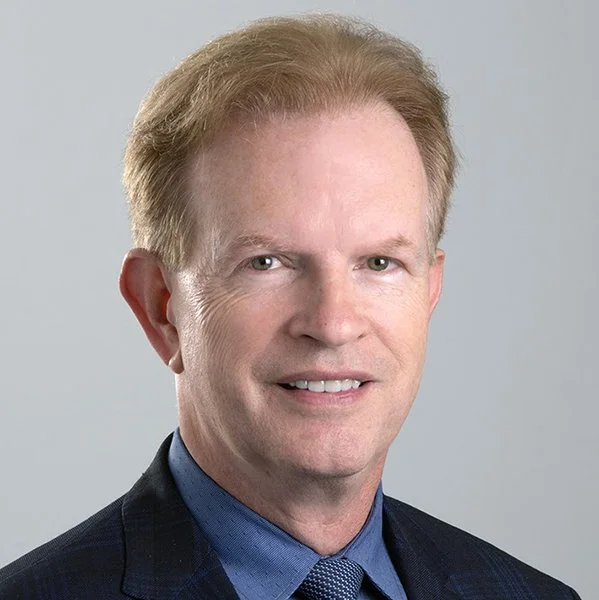 A headshot of John J. Leddy, MD, in a blue jacket and blue shirt.