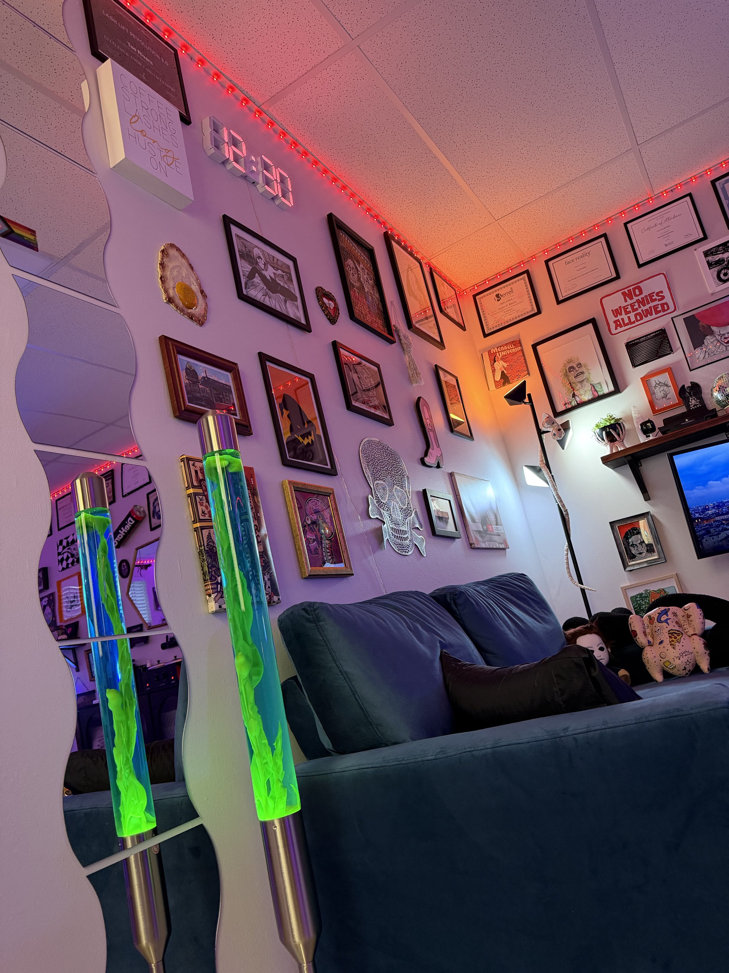 wavy mirror, lava lamp, and blue couch.Colorful Lighting maximalist decorated client seating area