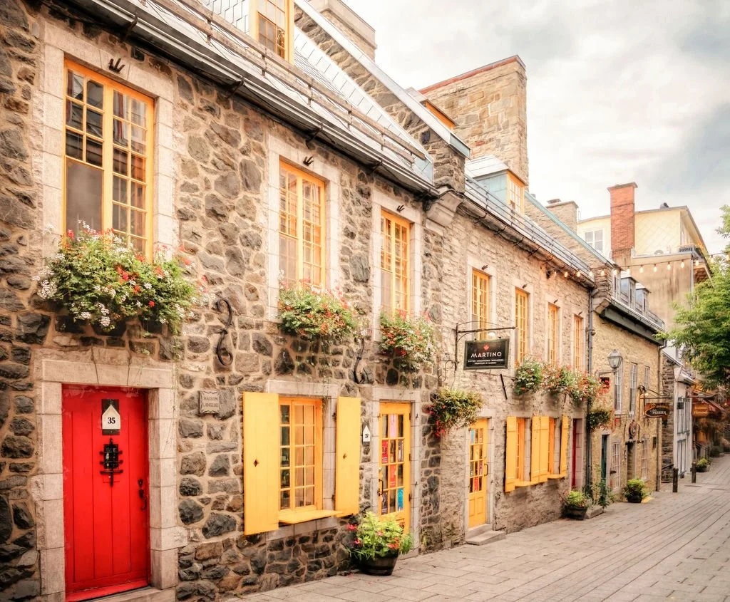 STONE BUILDING WITH YELLOW SHUTTERS AND RED DOOR IN QUEBEC CITY