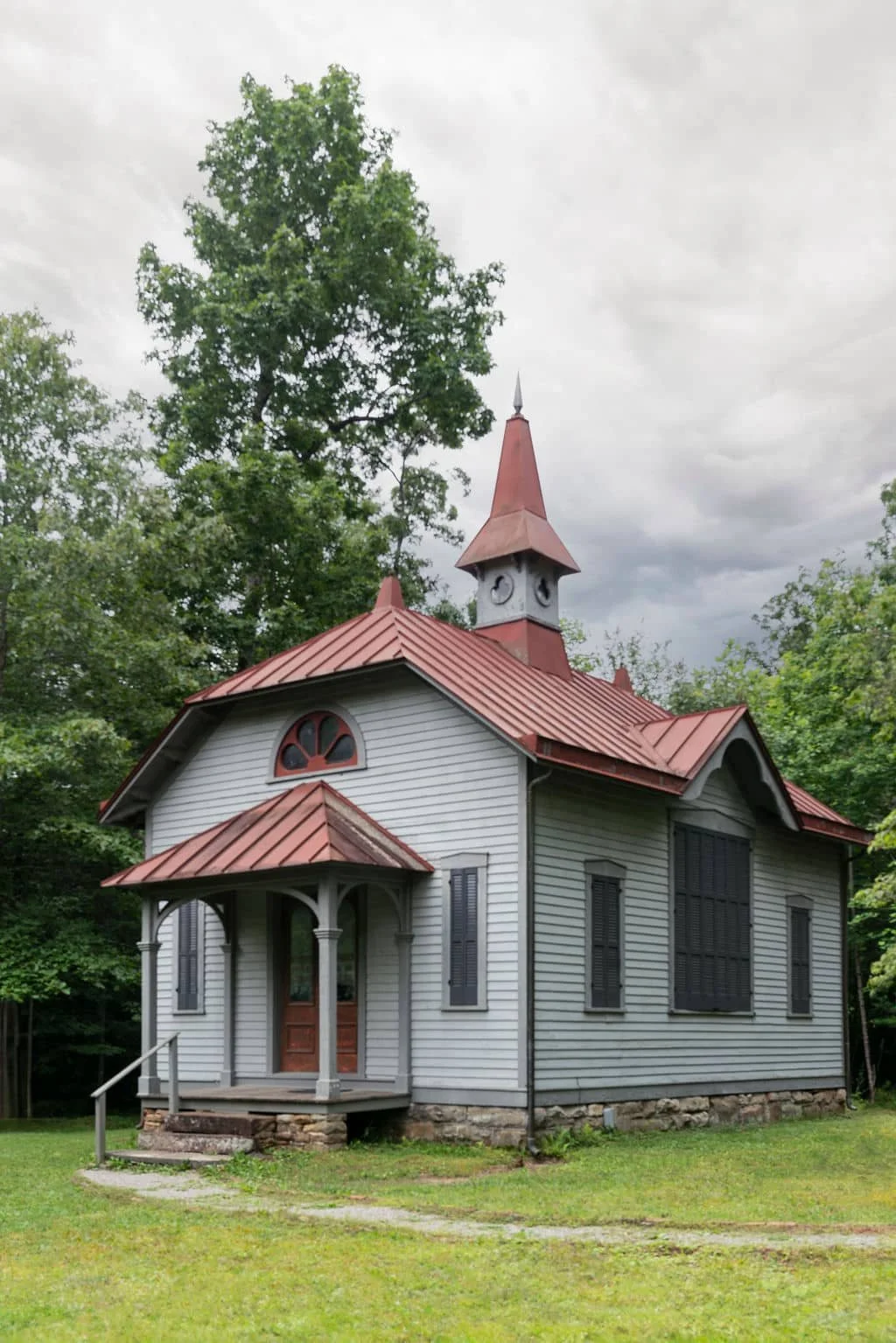 Small historic country library with red roof and steeple surrounded by trees in a peaceful rural setting