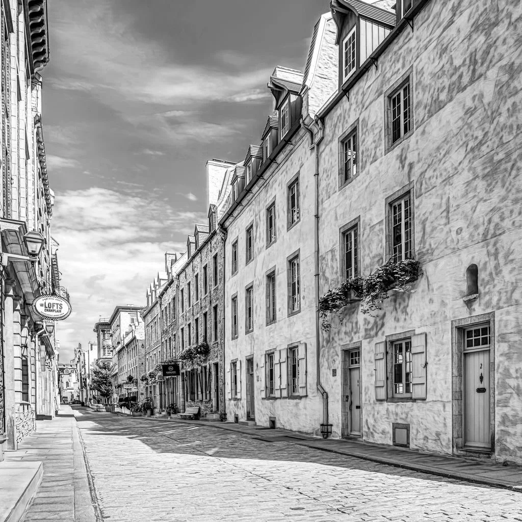 old Quebec city photo of a cobblestoned street with old buildings with flower boxes.