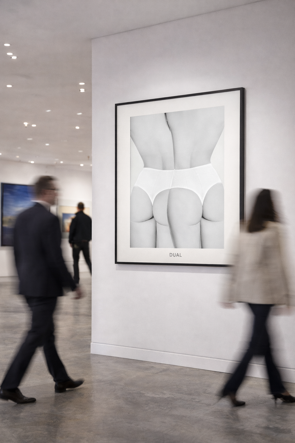 Black and white photograph of the back view of a person's lower body wearing lingerie, displayed in an art gallery. The word "DUAL" is printed at the bottom of the photograph.