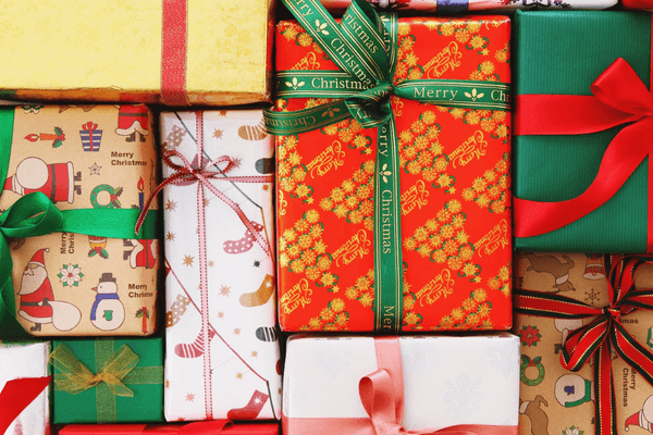 Stack of beautifully wrapped Christmas presents with red, green, and festive holiday gift boxes — perfect for employee and client holiday gift ideas