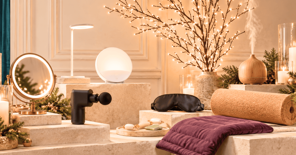 Corporate wellness gifts featuring a yoga mat, meditation cushion, massage gun, aromatherapy diffuser, mirror, and relaxation accessories.